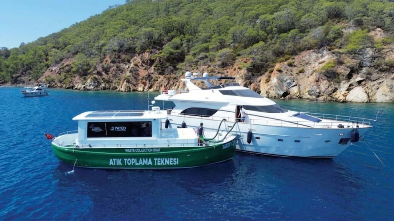 Bir yatın yanına yanaşmış atık toplama teknesi